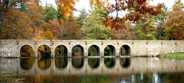 The stone arch bridge reflected in Byrd Lake at Cumberland Mountain State Park in autumn