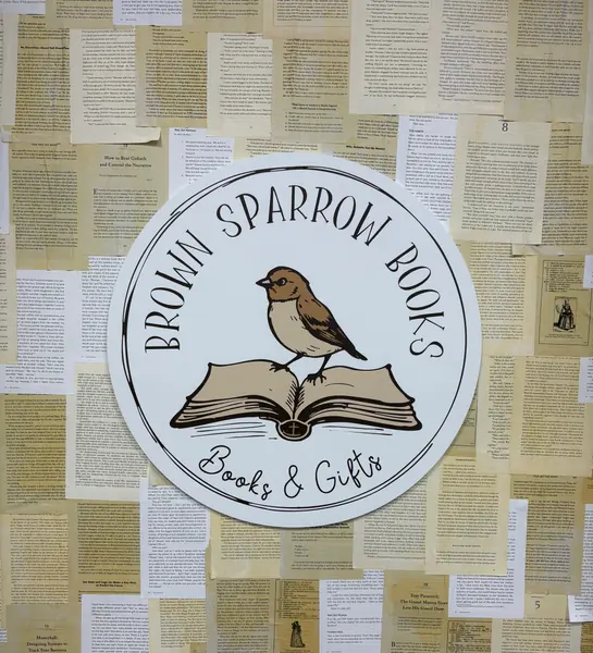 Brown Sparrow Books sign on a wall decorated with book pages