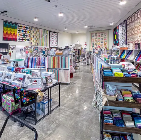 Fabric shelves and colorful quilts inside Mountain Top Fabrics and More