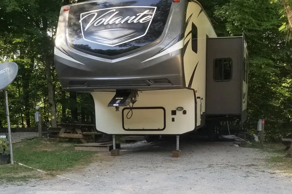 An RV on a shaded gravel site at Bean Pot Campground
